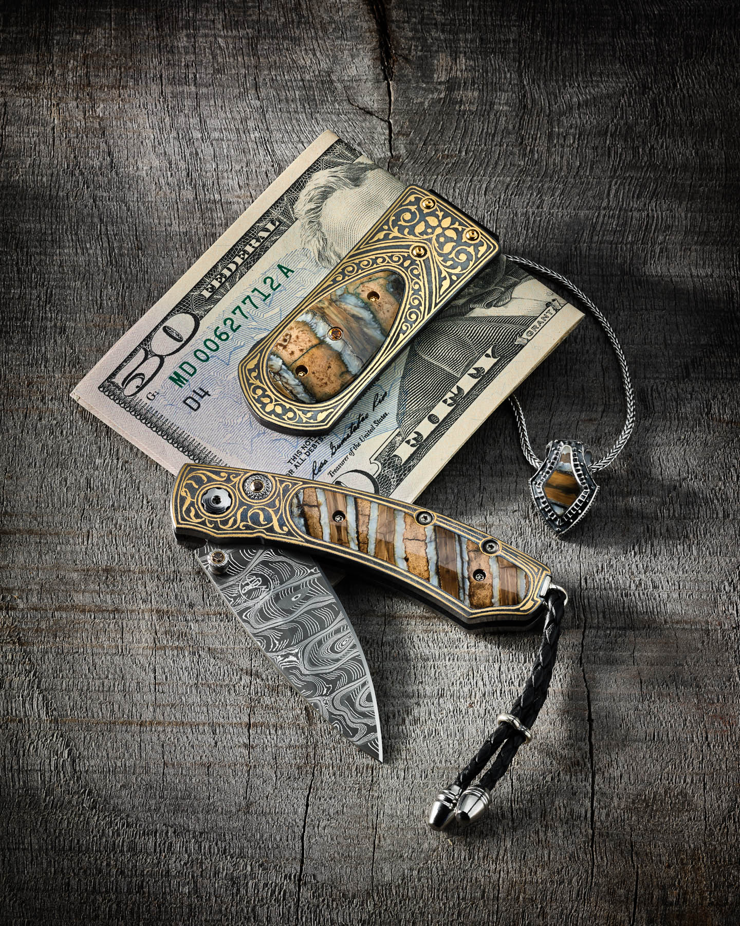 William Henry money clip, knife, and necklace on aged walnut