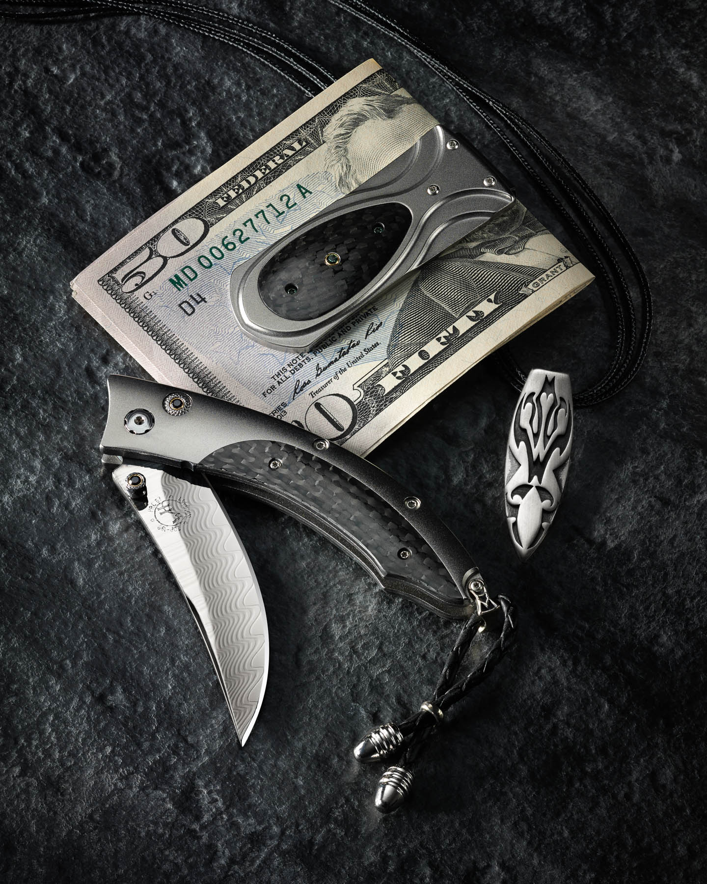 William Henry money clip, knife, and necklace on slate
