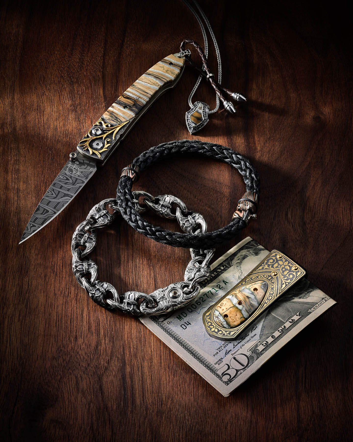 William Henry money clip, knife, and necklace on walnut